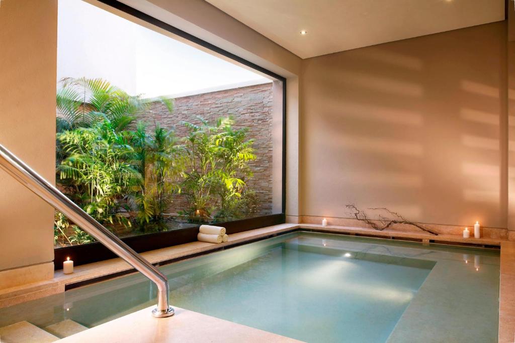 Indoor spa pool with handrail, candles, and planted courtyard view.