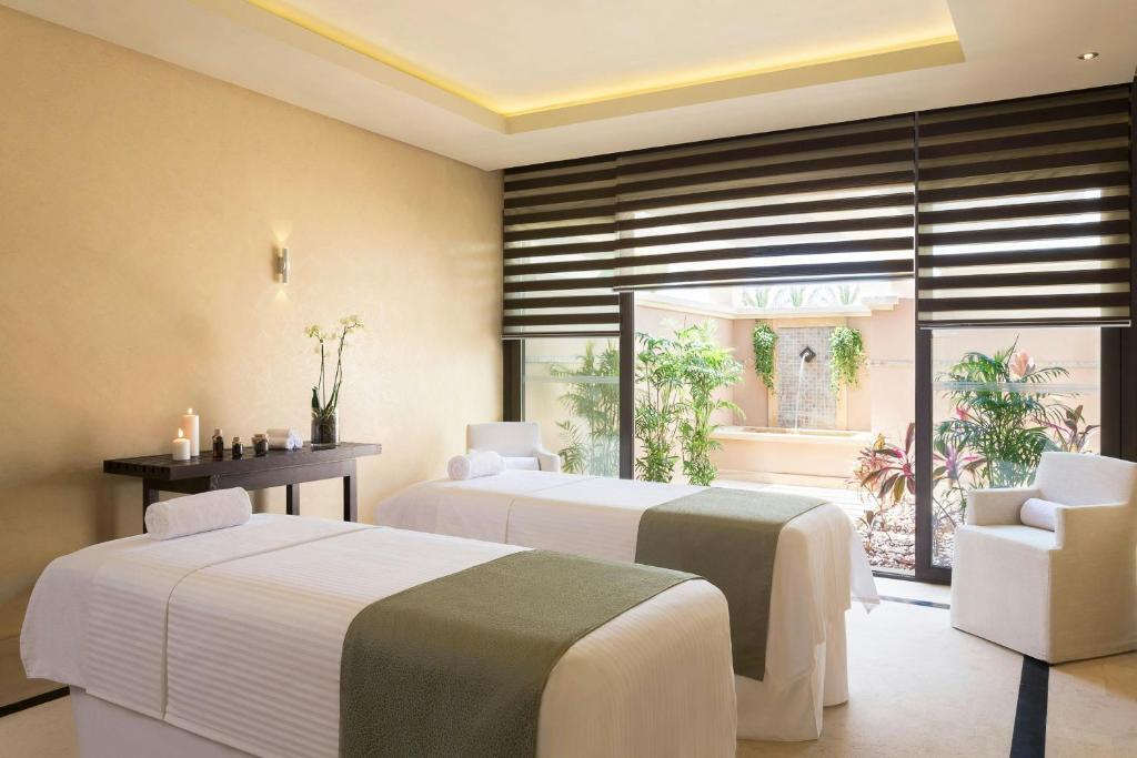 Spa treatment room with two massage beds, candles, and patio view for recovery sessions.