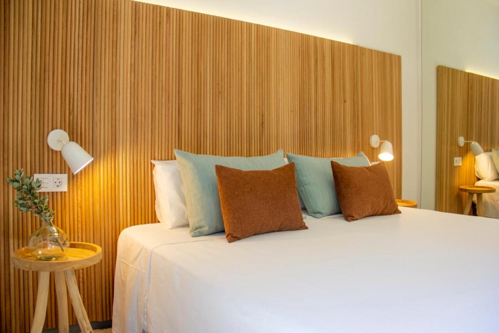 Modern double bedroom with wood headboard, bedside lamps, and decorative pillows.