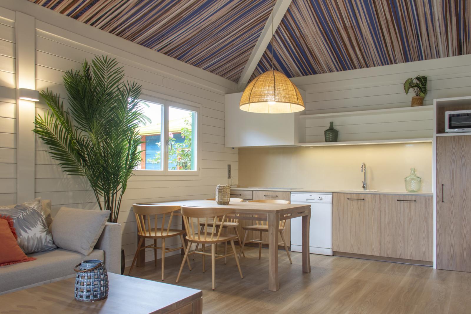 Cabin living area with sofa, dining table, and kitchenette under a striped ceiling.