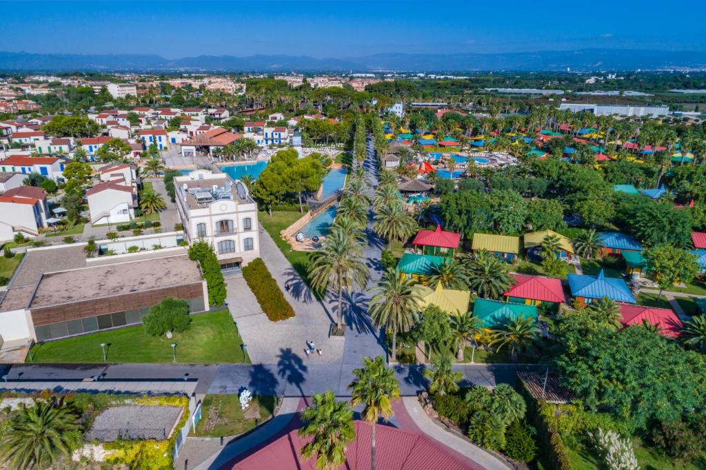 Aerial view of the resort with palm-lined avenues, pools, and colorful bungalows.