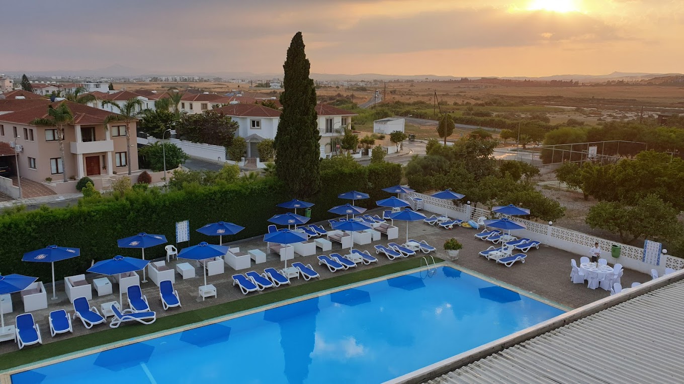 Elevated view of the outdoor pool area with sun loungers and umbrellas at sunset.