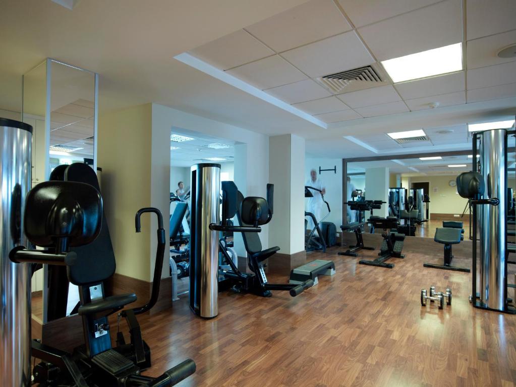 Fitness room with strength machines, dumbbells and mirrored workout area.