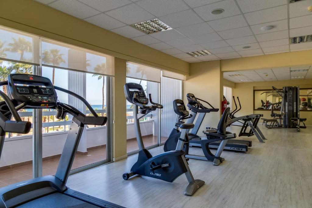 Gym with cardio and strength equipment beside large seafront windows.
