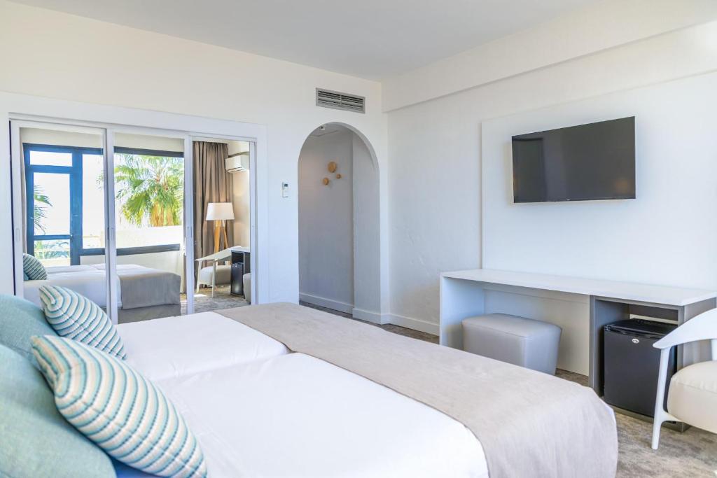 Gästezimmer mit Bett, TV, Schreibtisch und verspiegelten Schiebetüren.