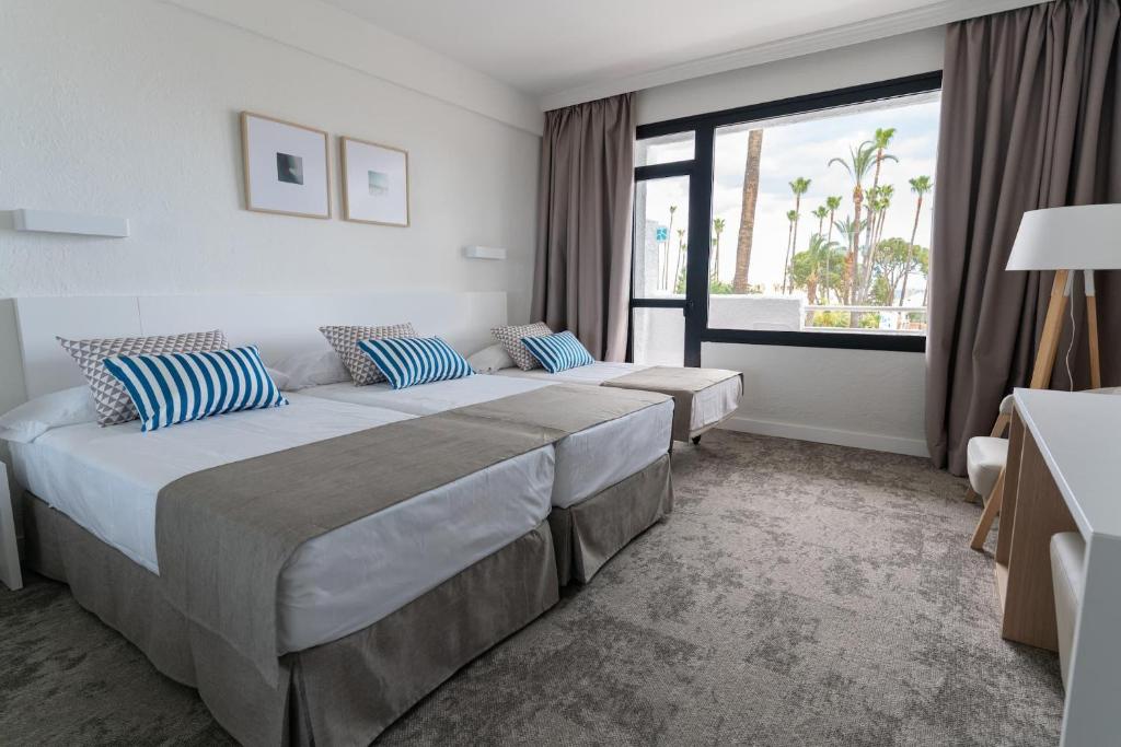 Gästezimmer mit drei Einzelbetten, Schreibtisch und großem Fenster.