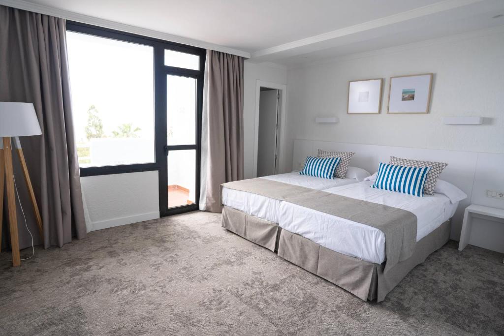 Helles Gästezimmer mit Doppelbett, großem Fenster und Balkontür.
