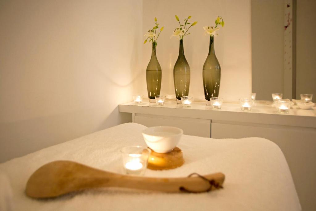 Spa-Behandlungsraum mit Massageliege, Kerzen und Blumenvasen für Regenerationseinheiten.