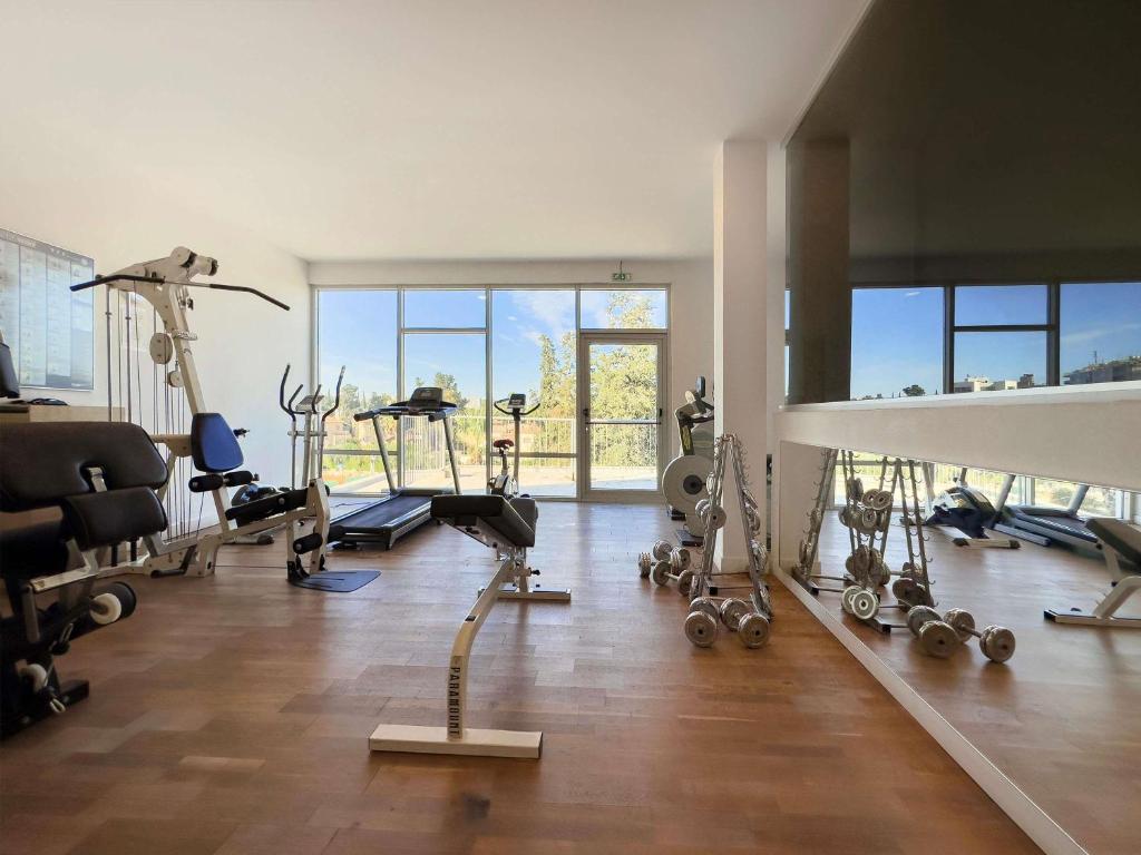 Hotel-Fitnessraum mit Cardiogeräten, Gewichten, Kraftgeräten und Spiegelwand für Workouts.