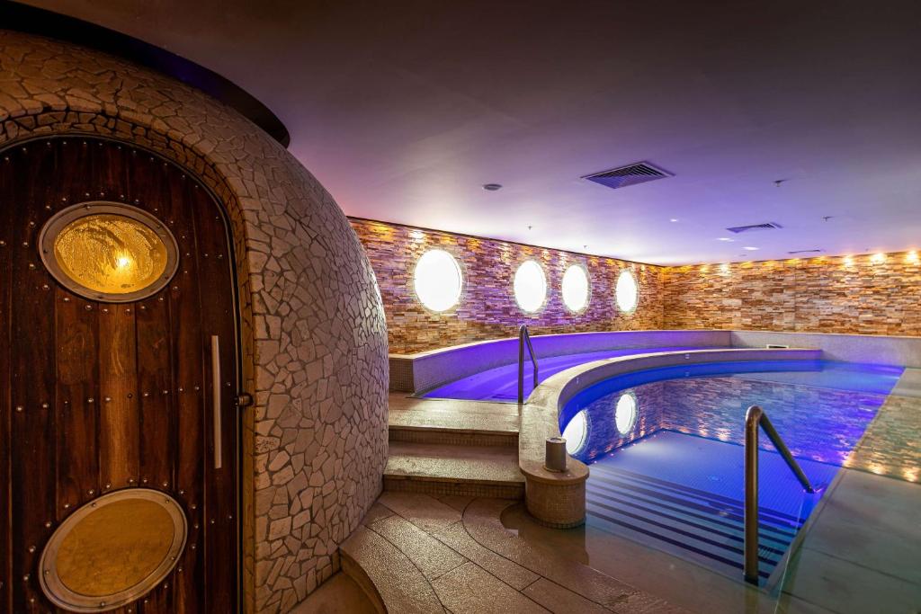 Gebogener Innen-Spa-Pool neben dem Eingang zu einem steinverkleideten Dampfraum.
