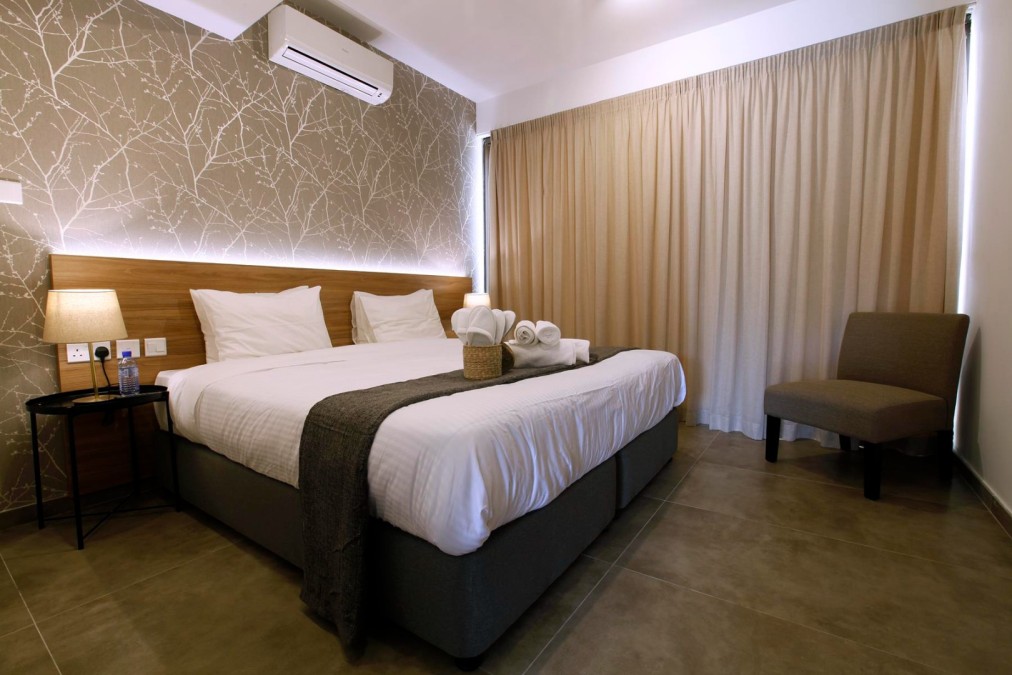 Modernes Hotelzimmer mit Doppelbett, neutraler Einrichtung und sanfter Beleuchtung neben beigen Vorhängen
