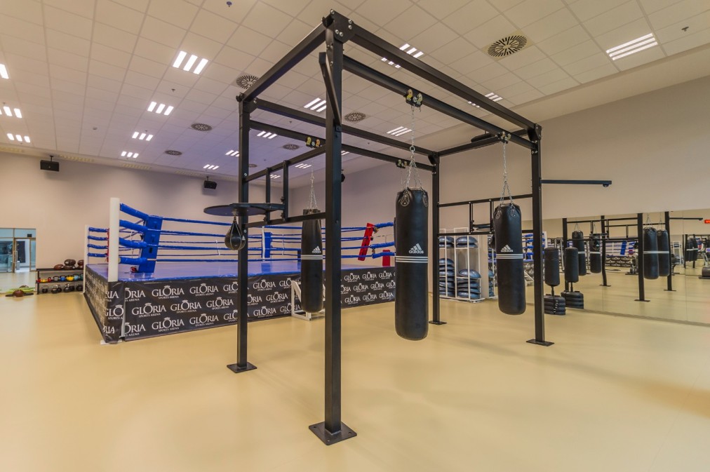 Eigener Boxbereich mit Ring und mehreren hängenden Sandsäcken für Schlagtraining. Die großzügige Trainingsfläche eignet sich für Technikdrills, Kondition und Gruppeneinheiten.