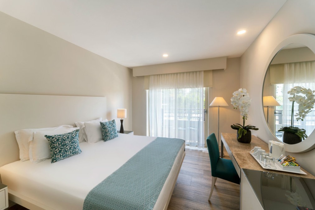 Doppelzimmer mit Balkontüren, Schreibtisch und Schminkspiegel.