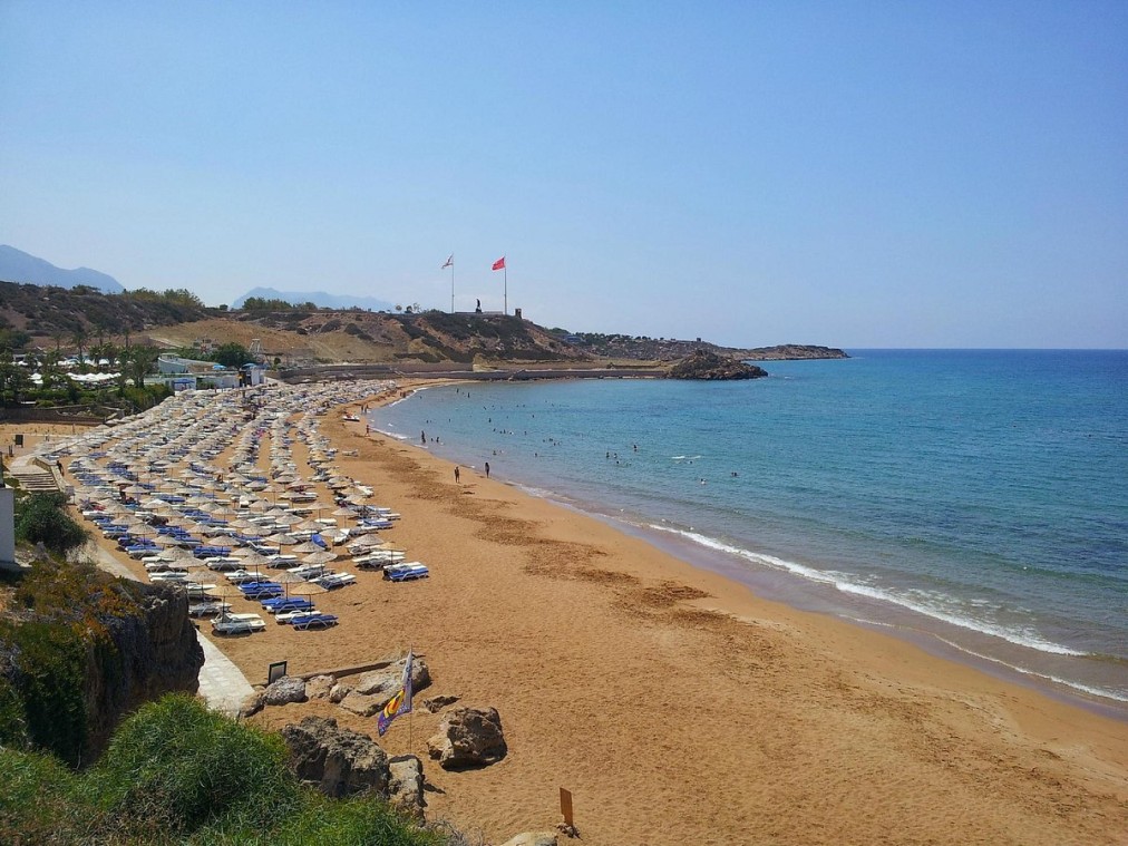 Breiter Sandstrand mit Sonnenschirmen und Sonnenliegen entlang der Küste