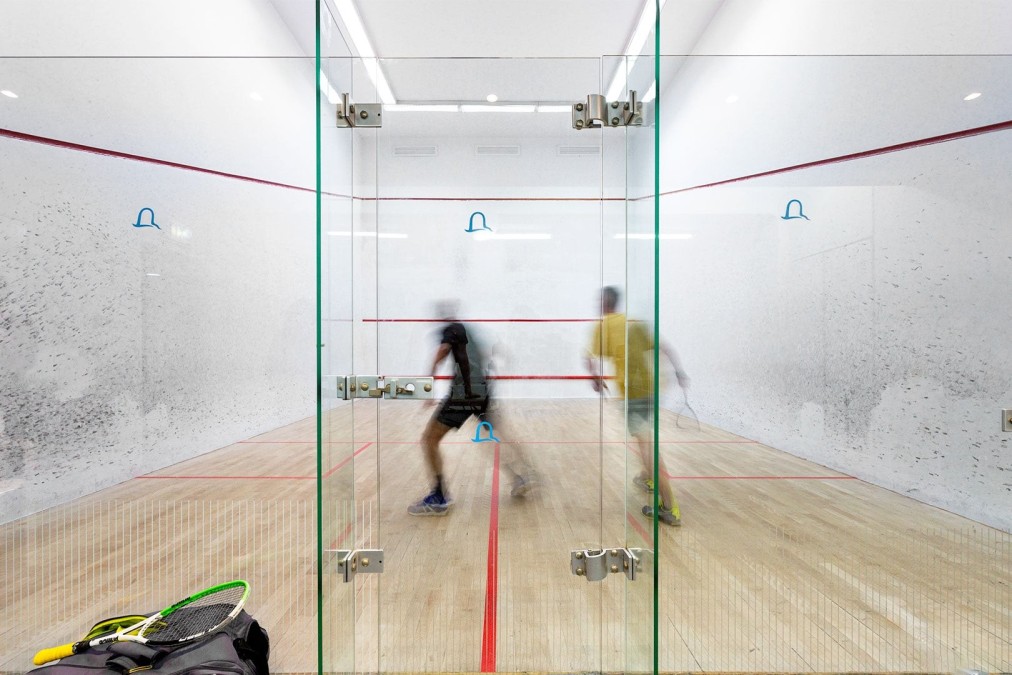 Zwei Athleten spielen Squash in einem verglasten Innenplatz während einer Trainingseinheit