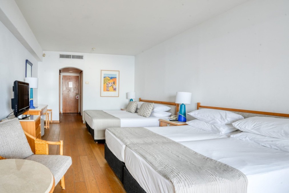 Geräumiges Hotelzimmer mit mehreren Betten und Holzmöbeln für die Unterbringung von Teams