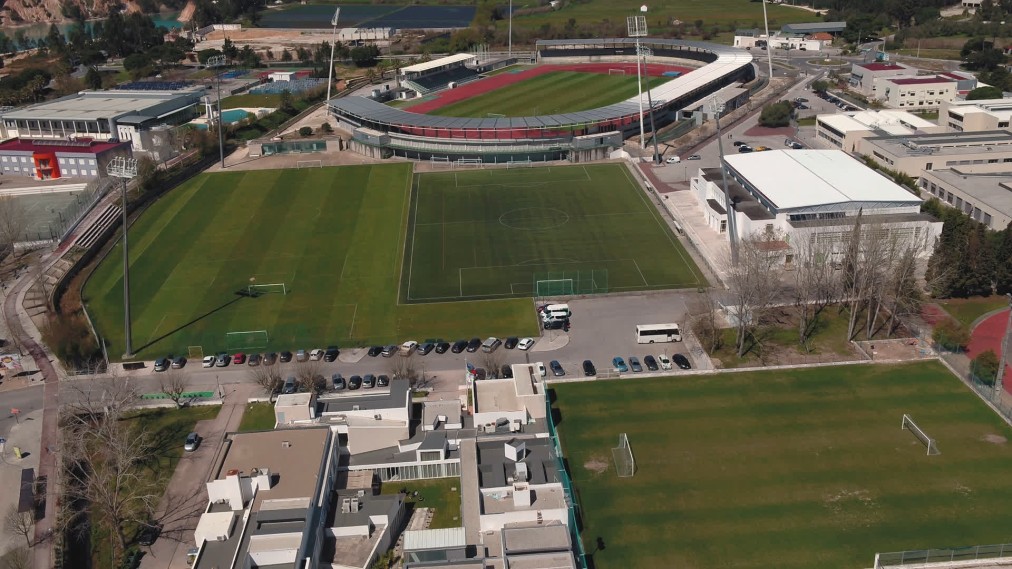Luftaufnahme eines Sportkomplexes mit Fußballfeldern, Stadion, Sporthalle und umliegenden Gebäuden.