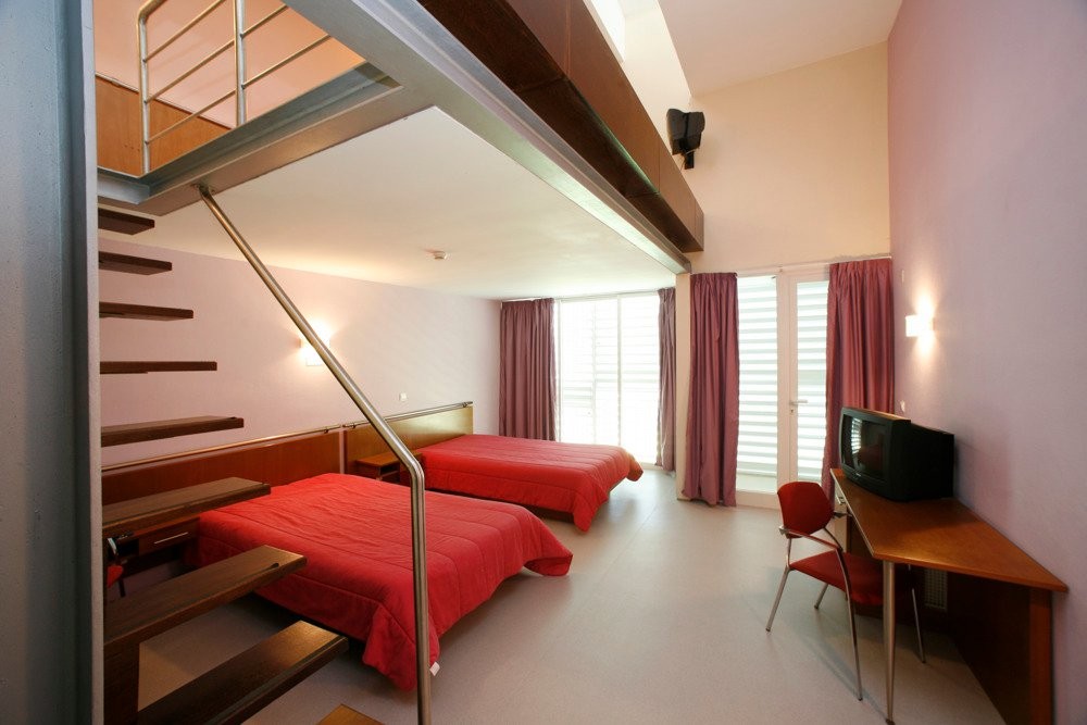 Maisonette-Zimmer mit zwei Betten, Treppe und Schreibtisch mit Fernseher.