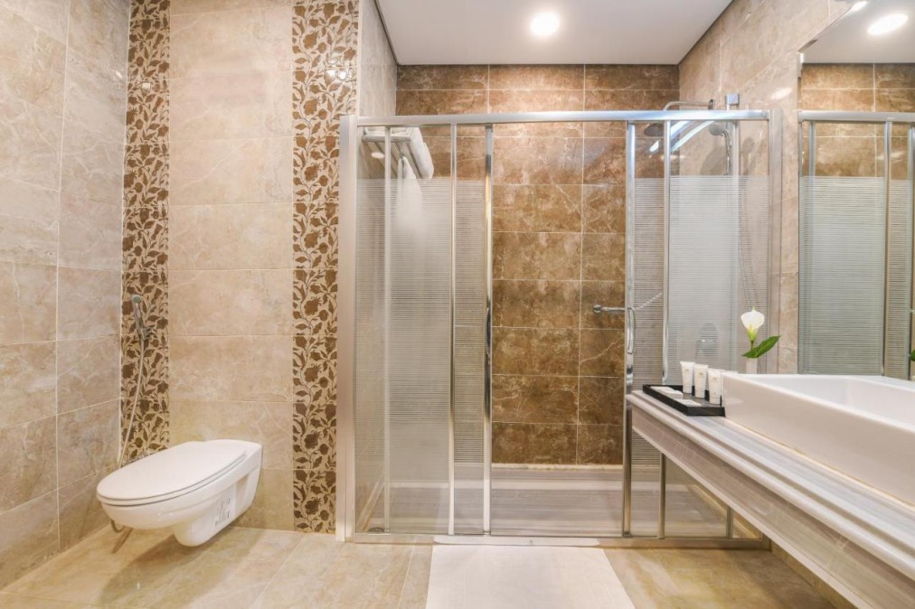 Modernes Badezimmer mit begehbarer Dusche, Glastüren und gefliesten Wänden