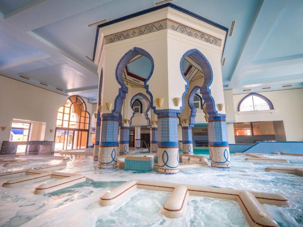 Großer Indoor-Spa-Pool mit Mosaiksäulen und Wasserfeatures zur Regeneration nach dem Training