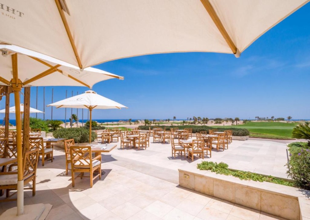 Außenterrasse mit Sonnenschirmen und Blick auf Golfplatz und Meer, ideal für Team-Mahlzeiten