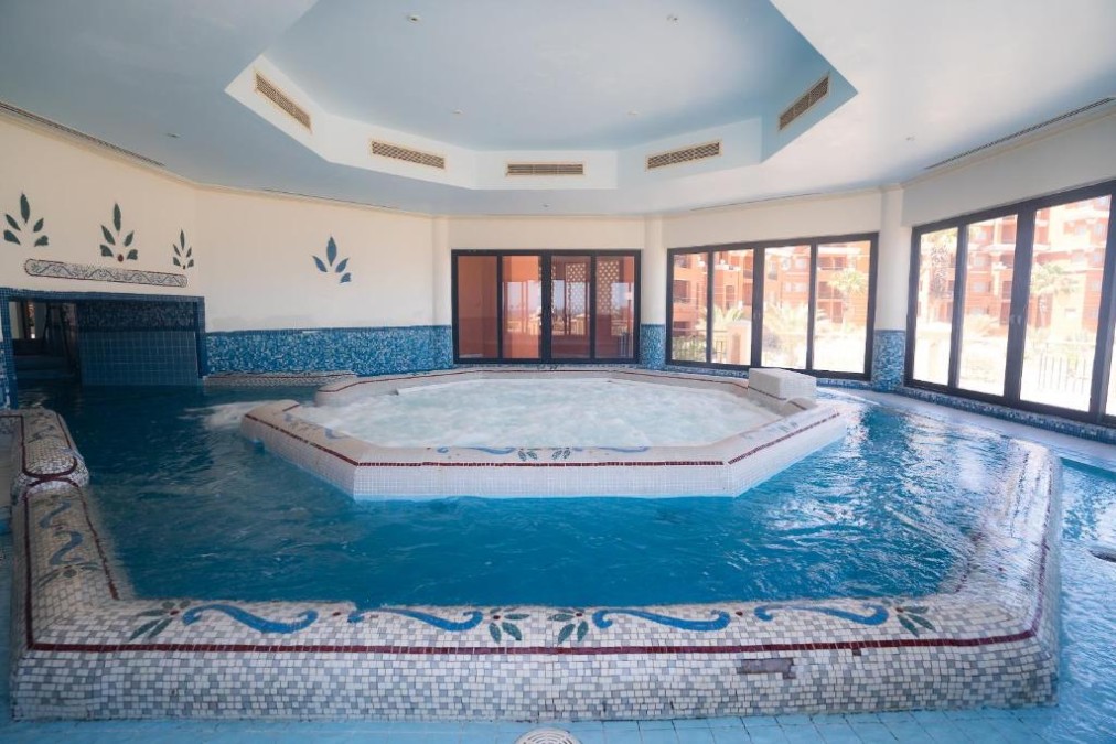 Indoor-Spa-Pool mit zentraler Whirlpool-Insel und Panoramafenstern, ideal zur Regeneration nach dem Training