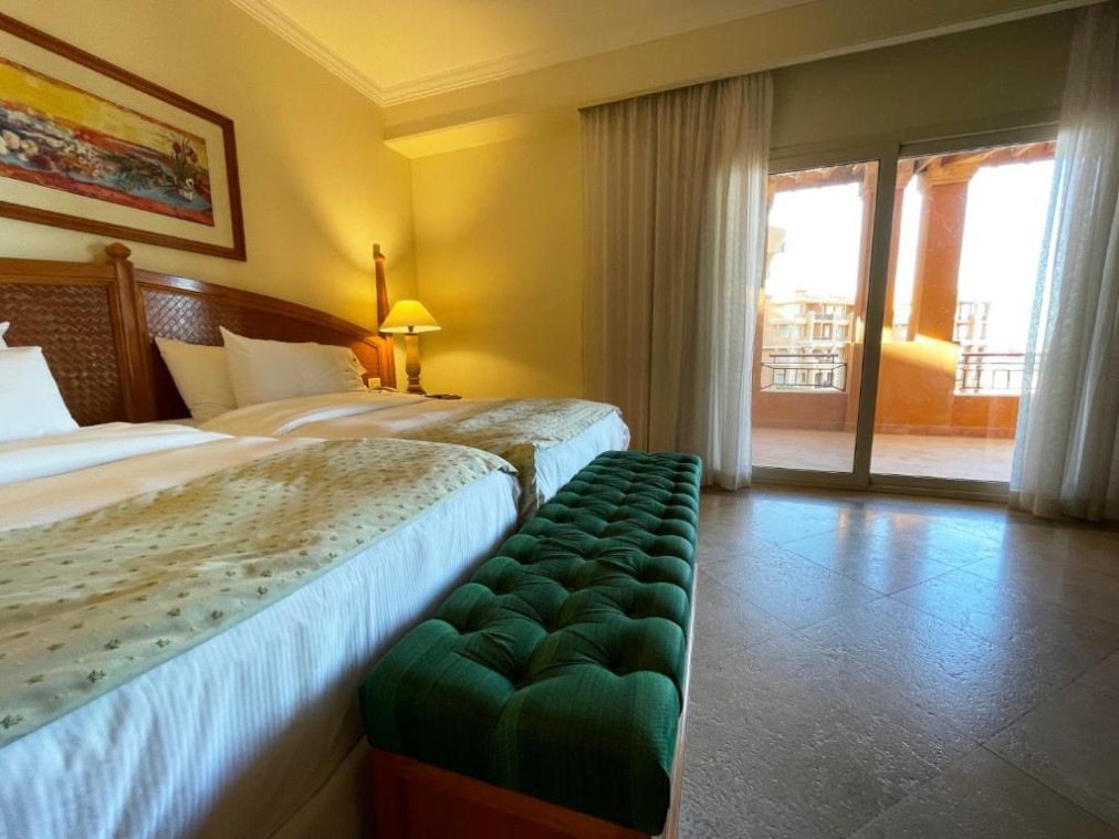 Schlafzimmer mit zwei Betten und Balkonzugang für komfortable Team-Unterkunft.
