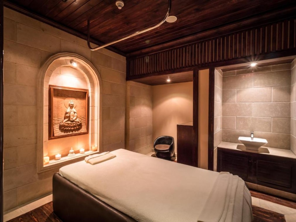Warm beleuchteter Spa-Behandlungsraum mit Massageliege, Kerzen und Deko zur Regeneration