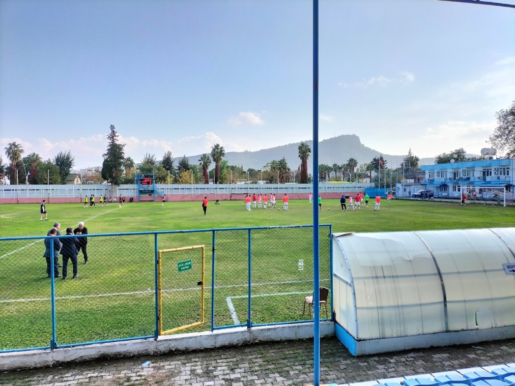 Fußball-Trainingscamp: Teamdrills auf Rasenplatz im Stadion, mit Auswechselbank und Bergkulisse.