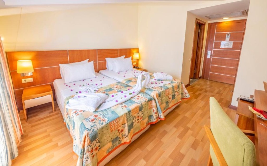 Zweibettzimmer mit zwei Einzelbetten, Nachttischlampen, Schreibtisch und Holzfußboden.