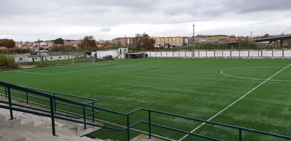 Leerer Kunstrasen-Fußballplatz, von der Tribüne aus an einem bewölkten Tag gesehen.