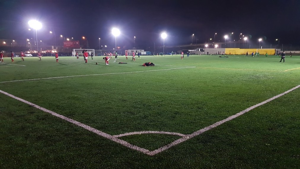 Flutlichtbeleuchteter Kunstrasen-Fußballplatz während einer abendlichen Trainingseinheit.