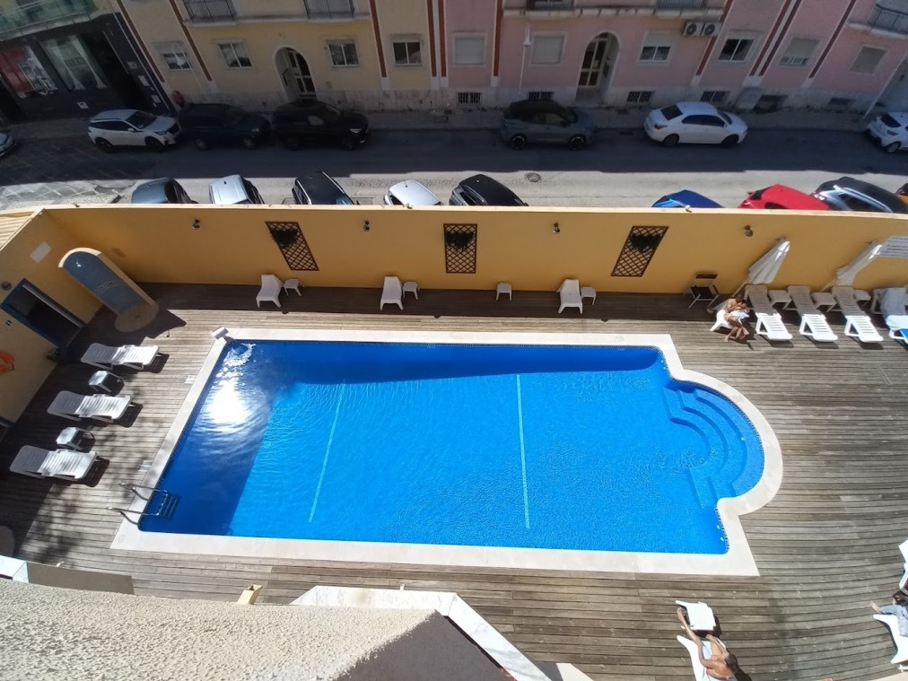 Außenpool und Sonnenliegen im Hotelinnenhof aus der Vogelperspektive.