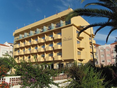 Außenansicht des mehrstöckigen Hotelgebäudes mit Balkonen und Gartenanlage.