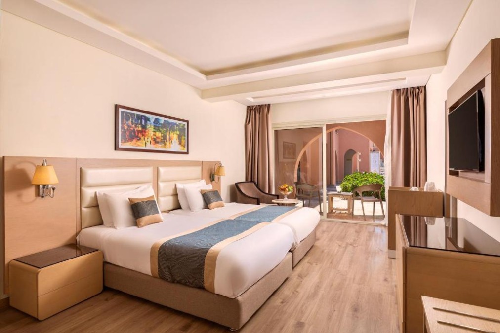 Helles Hotelzimmer mit zwei Einzelbetten, Wandkunst und Terrasse mit Sitzgelegenheit im Freien