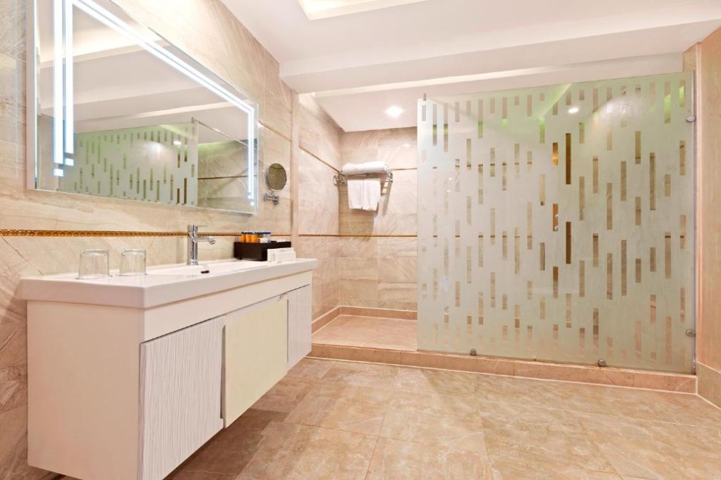 Modernes Hotelbadezimmer mit großem Spiegel, Waschbecken und verglaster Dusche mit Milchglasdesign