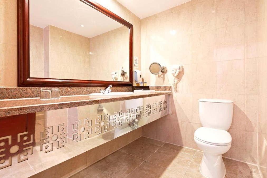 Badezimmer mit großem Spiegel, Waschbecken und Toilette in beigen Fliesen