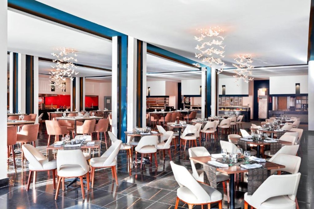 Modernes Restaurant mit weißen Stühlen, braunen Akzenten und dekorativer Beleuchtung