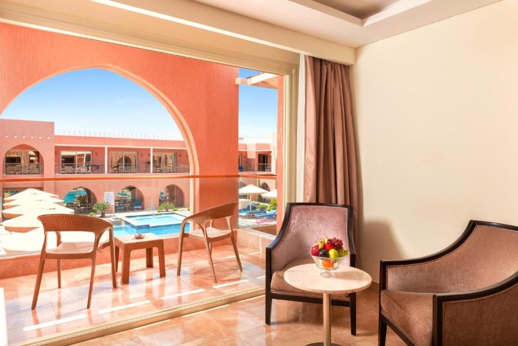 Balkon mit Stühlen und Tisch mit Blick auf den Poolbereich eines Resorts