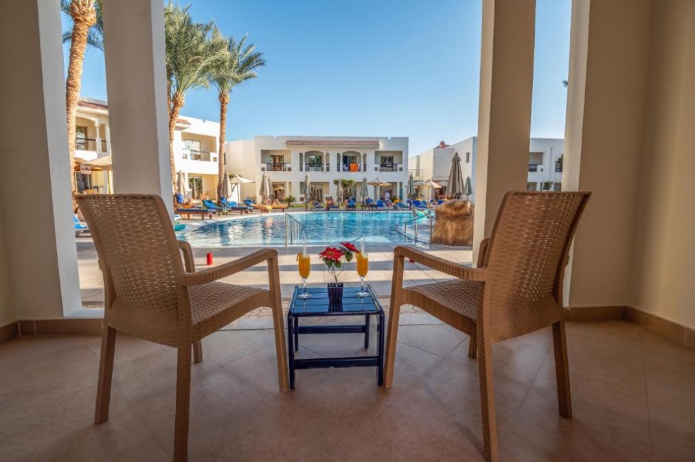 Terrasse mit zwei Korbstühlen und kleinem Tisch mit Blick auf den Pool und die Resortgebäude