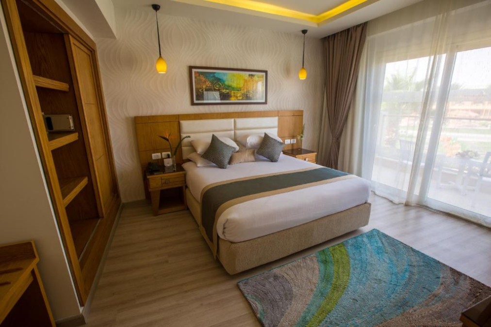 Helles Doppelzimmer mit großem Bett, Kleiderschrank und Schiebetüren zum Balkon/zur Terrasse.