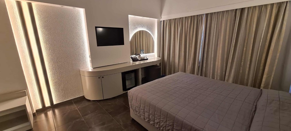Doppelzimmer mit Akzentbeleuchtung, Schreibtisch, Minibar und bodenlangen Vorhängen.