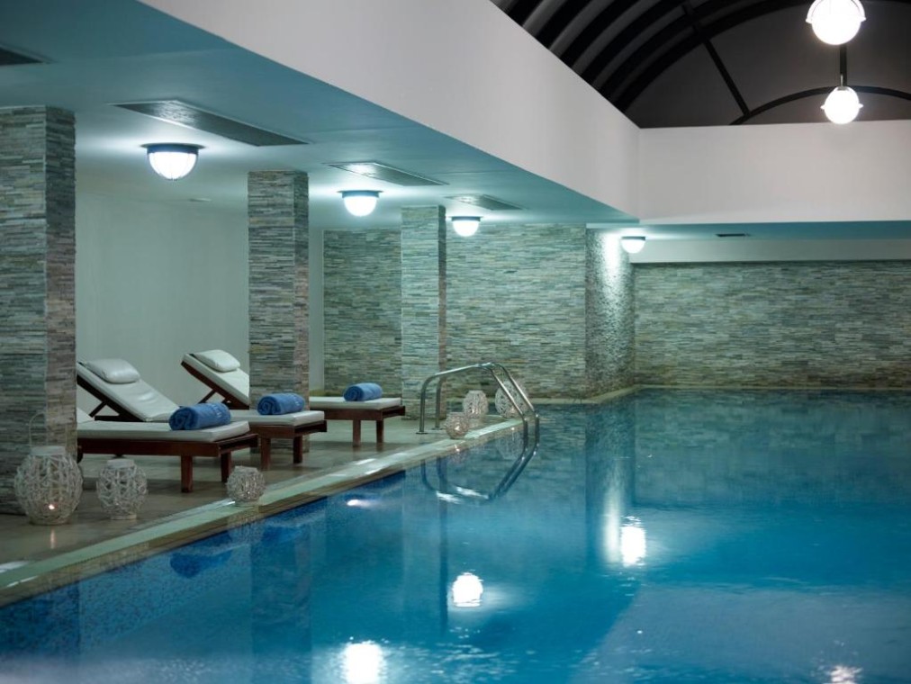 Innenpool im Spa mit Liegen, Handtüchern und Steinwänden.