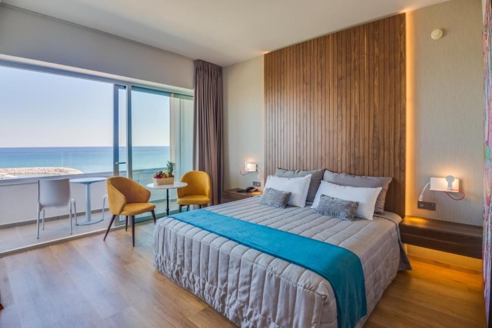 Gästezimmer mit Doppelbett, Balkonbestuhlung und Meerblick.