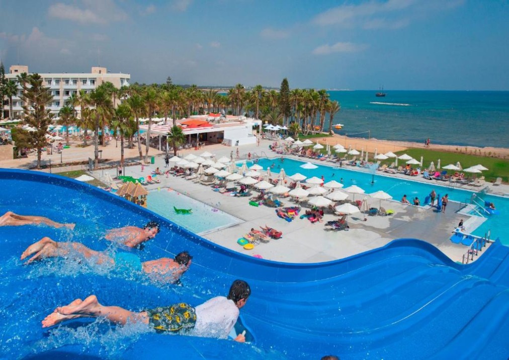 Weite Ansicht von Wasserrutschen, Außenpools und Hotelanlage am Meer.