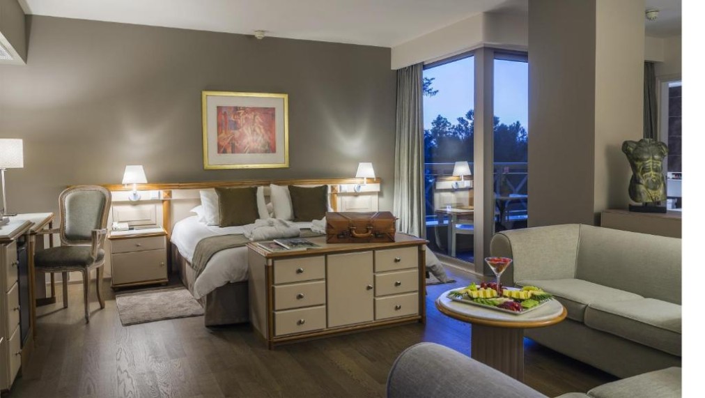 Geräumiges Gästezimmer mit Doppelbett, Sitzecke und Zugang zum Balkon.