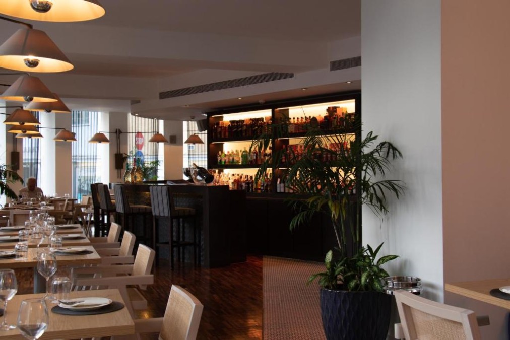 Restaurant- und Barbereich mit Esstischen, Pendelleuchten und beleuchteten Regalen.