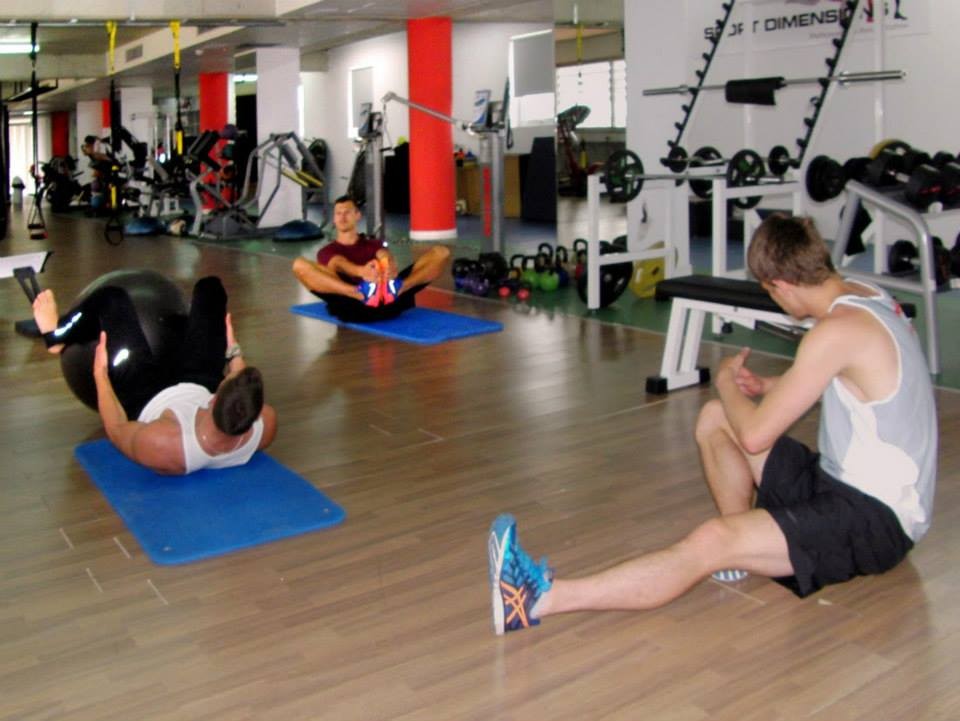 Athlètes effectuant des exercices au sol sur tapis avec équipement de gymnastique en arrière-plan
