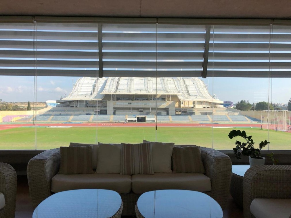 Espace salon avec canapés et grande fenêtre donnant sur le stade et la piste de course