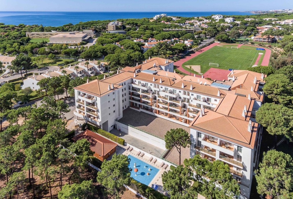 Vue aérienne du complexe au bord de la mer avec piste d'athlétisme et terrain de football.